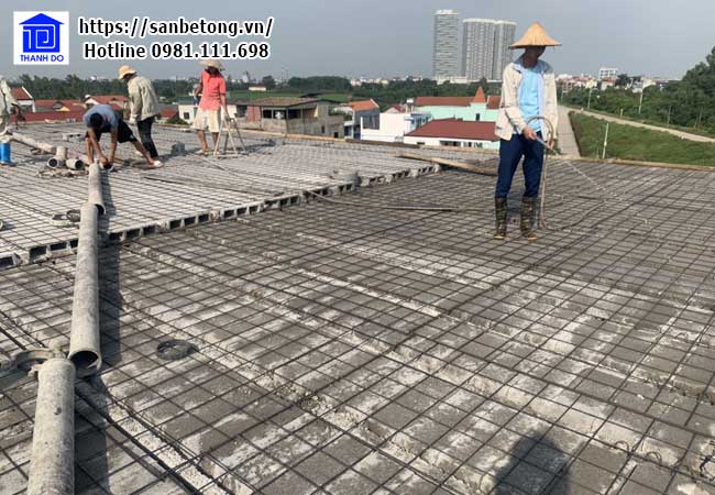 Công nhân tưới nước để lớp bê tông tươi kết dính tốt hơn